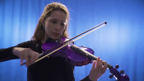 Close-up-of-young-female-musician-playing-violin-on-stage-and-her-violin.